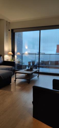 een woonkamer met een tafel en een groot raam bij Tranquilo y relajante Apartamento familiar in Esplugues de Llobregat