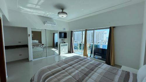 Dormitorio blanco con cama y ventana grande en Elegante Blue Marine Apartamento Juan Dolio, en Juan Dolio