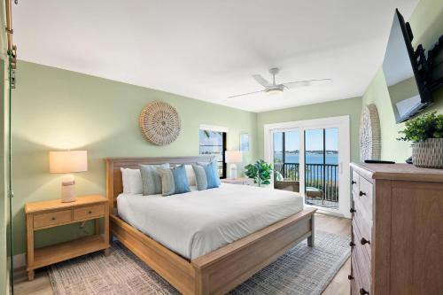 een slaapkamer met een bed, een televisie en een balkon bij Coquina Moorings 203 in Bradenton Beach