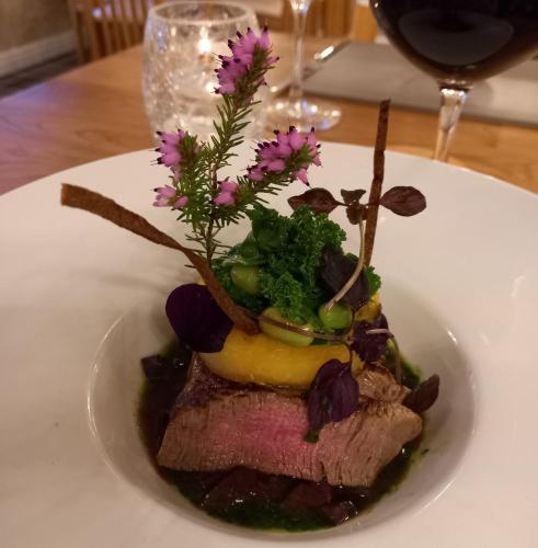a white plate with a piece of meat with flowers on it at Orchard Lodge & Wolds Restaurant in Cayton