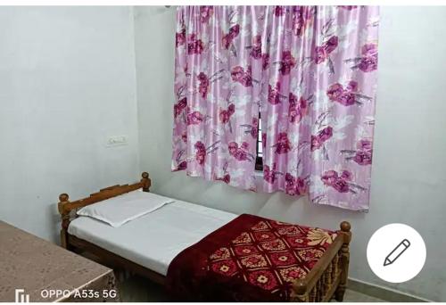 a bedroom with a bed and a window with a curtain at Sree Paramahamsa in Varkala