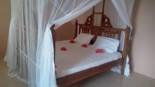 MINAZI BEACH BUNGALOWS في نونغوي: غرفة نوم مع سرير مع زهور حمراء عليه