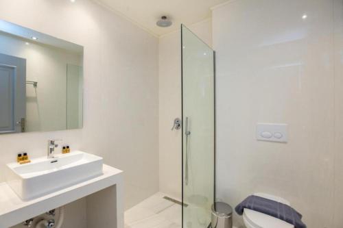 La salle de bains est pourvue d'un lavabo et d'une douche en verre. dans l'établissement Elisabeta 3 guests apartment, à Limenaria