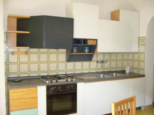 uma cozinha com armários brancos e um forno com placa de fogão em Residence Giannella - Pitosforo 46 em Giannella