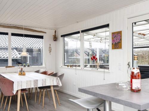 cocina con mesa, sillas y ventanas en Holiday home Juelsminde LII, en Sønderby