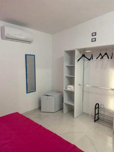 een witte kamer met een bed en een spiegel bij Oriente Rooms in San Nicola Arcella