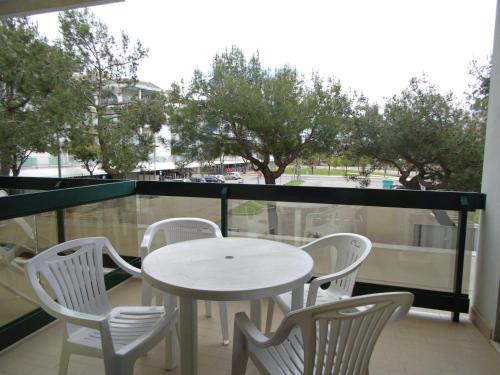 une table et des chaises blanches sur un balcon arboré dans l'établissement COSTA DEL SOL, à Lido di Jesolo
