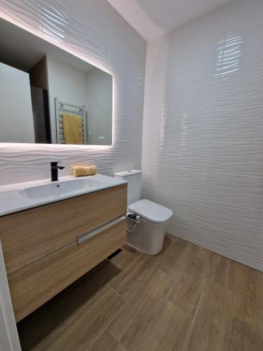a bathroom with a sink and a toilet and a mirror at Aquí es in Badajoz