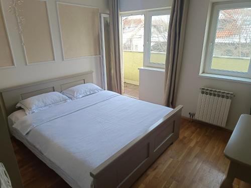 a bedroom with a white bed with two windows at 塞尔维亚悦客之家民宿 in Belgrade