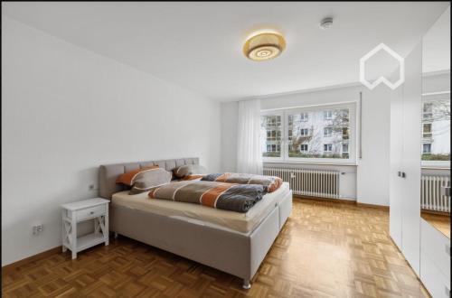 a white bedroom with a bed and a window at Apartment "Wirtschaftswunder" in Rheinfelden