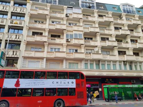 Ein roter Doppeldeckerbus parkte vor einem Gebäude in der Unterkunft CS Apartment in Skopje