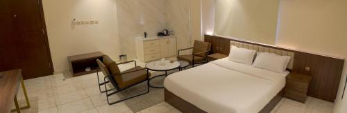 Arica hotel apartments في تبوك: غرفة نوم بسرير وطاولة وكراسي