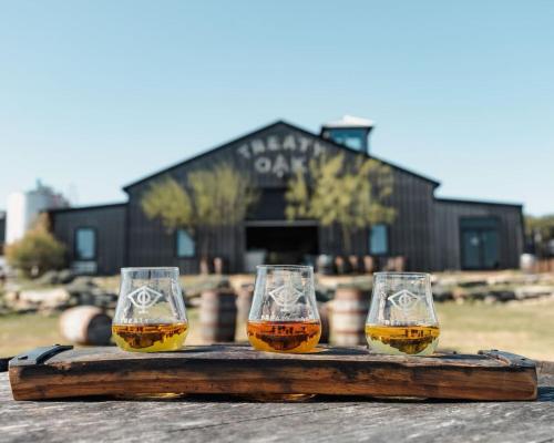 three glasses of beer sitting on a wooden tray at Luxe Modern Treehouse w Heated Pool, Firepit in Dripping Springs