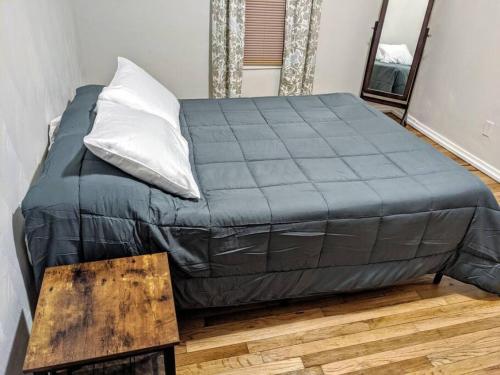 uma cama com um cobertor azul e uma mesa de madeira em Moline 1 BR Near TaxSlayer and Downtown em Moline