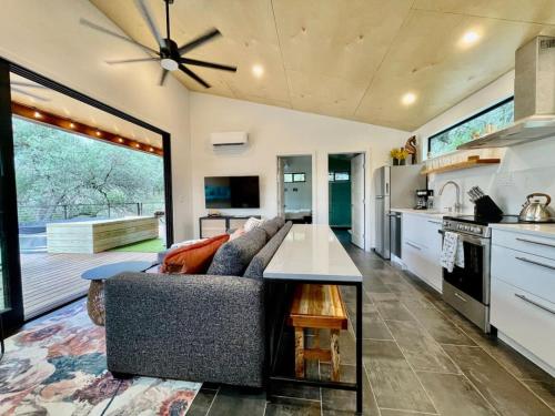 a living room with a couch and a kitchen at Gorgeous Modern Cabin w Heated Pool, Firepit in Dripping Springs