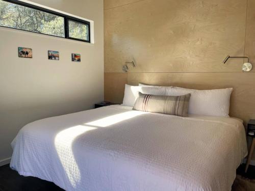 a bedroom with a large white bed with a window at Gorgeous Modern Cabin w Heated Pool, Firepit in Dripping Springs