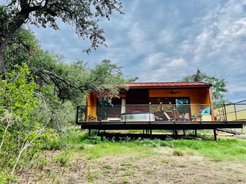 a house with a large deck in the woods at Gorgeous Modern Cabin w Heated Pool, Firepit in Dripping Springs