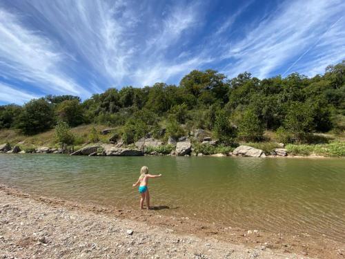 a young girl standing on the shore of a river at Gorgeous Modern Cabin w Heated Pool, Firepit in Dripping Springs