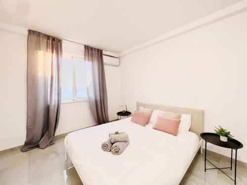 una camera bianca con un grande letto bianco con cuscini rosa di SUNSHINE SUITS - BRAND NEW APARTMENTS a Msida