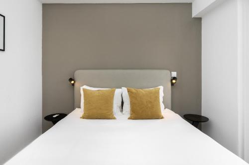 1 dormitorio con cama blanca y almohadas amarillas en WHome | 270º Panoramic View Premium Apartment en Lisboa