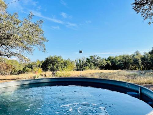 a bath tub filled with water next to a field at Cozy Cabin w Pvt Heated Pool Under Epic TX Stars in Dripping Springs