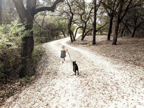a little girl walking a dog on a dirt road at Cozy Cabin w Pvt Heated Pool Under Epic TX Stars in Dripping Springs