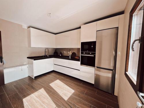 a kitchen with white cabinets and a stainless steel refrigerator at Casa rural el Retiro de Sancho in Cózar