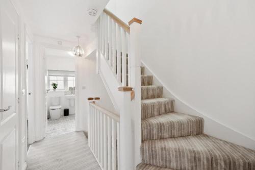 a hallway with a staircase with a toilet and a bathroom at Modern 4 Bedroom House with Parking Basildon in Laindon