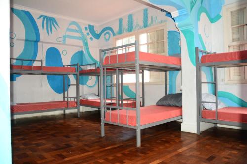 three bunk beds in a room with a mural at AKKUI HOSTEL in Sao Paulo