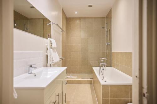 een badkamer met 2 wastafels, een douche en een bad bij The West Kensington Hideout - Cozy 2BDR Flat with Garden in Londen