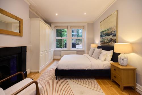 een slaapkamer met een bed en een open haard bij The West Kensington Hideout - Cozy 2BDR Flat with Garden in Londen