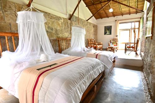 a bedroom with two beds with white sheets at Cabañas Tosepan Kali in Cuetzalán del Progreso