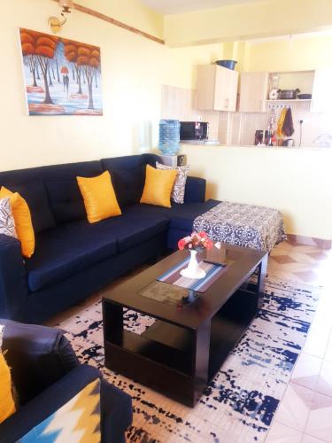 un soggiorno con un divano blu e un tavolino da caffè di Cosy 1 Bedroom TRM,Thika Rd a Nairobi