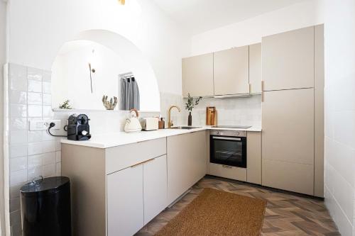 - une cuisine blanche avec des placards blancs et un tapis dans l'établissement Spacieux T2 au coeur de la Camargue - 10mn Plage, à Salin-de-Giraud