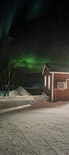 a house with a green aurora in the sky at Micke o Ritas stuga in Björkliden