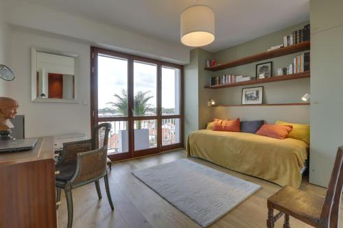 une chambre avec un lit, un bureau et une fenêtre dans l'établissement Auteuil - Appartement lumineux rénové, à Biarritz