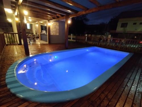 a blue hot tub on a deck at night at Pousada Bombinhas House in Bombinhas