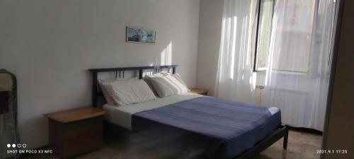 ein Schlafzimmer mit einem Bett mit einer blauen Decke und einem Fenster in der Unterkunft casa mare Spotorno in Spotorno