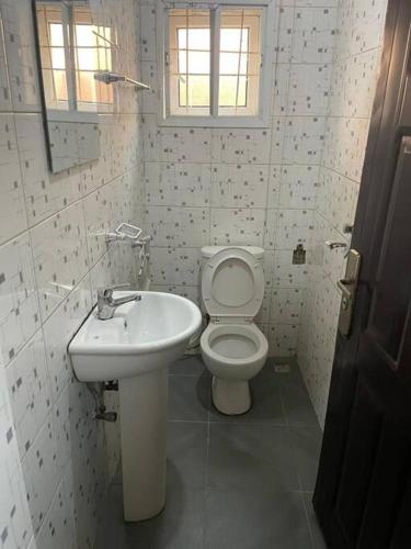 a white bathroom with a toilet and a sink at 2 Bedroom and a kitchen. in Abuja