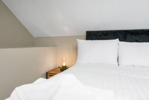 a bed with white sheets and a candle on a night stand at Wiverton Apt #5 - Central Location - Free Parking, Fast WiFi and Smart TV by Yoko Property in Nottingham