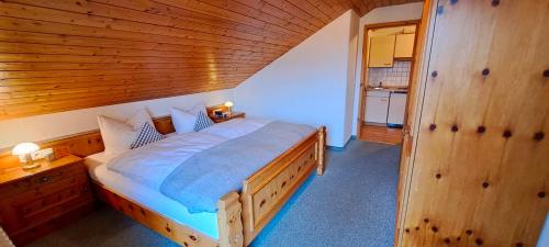 a bedroom with a large bed with a wooden ceiling at Gästehaus Krumbacher in Bolsterlang