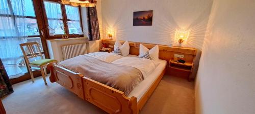 a bedroom with a large wooden bed with two lamps at Gästehaus Krumbacher in Bolsterlang