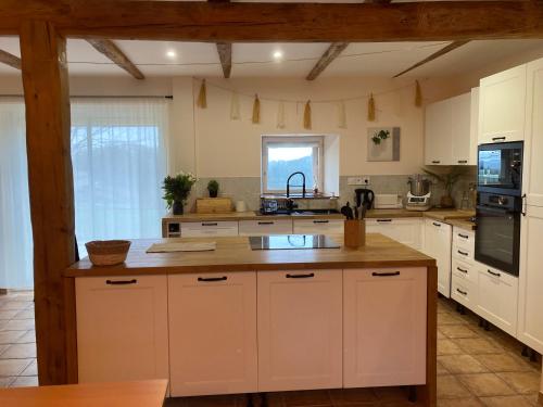 uma grande cozinha com armários brancos e um lavatório em La maisonnée Auvergnate em Auzelles