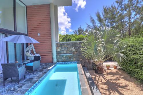 a swimming pool with a table and an umbrella next to a house at SG5 l Le Turquoise - second line Beachfront in Cap Malheureux