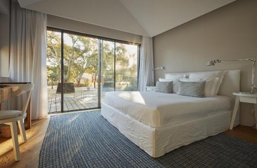 a bedroom with a large bed and a large window at Sublime Comporta Country Retreat & SPA in Comporta