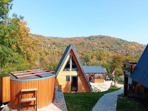 a small house with a pointed roof with a hill in the background at CARPATINA Rustic House in Runcu