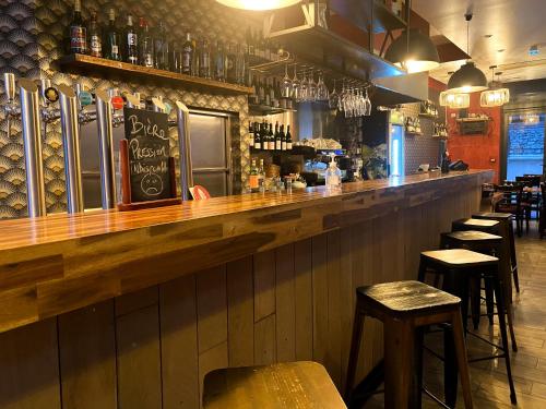 un bar con barra de madera y algunos taburetes en Chambres Pasteur en Montreuil