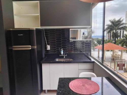 a kitchen with a black refrigerator and a table at Apart hotel otima localizaçao em Brasilia in Brasília