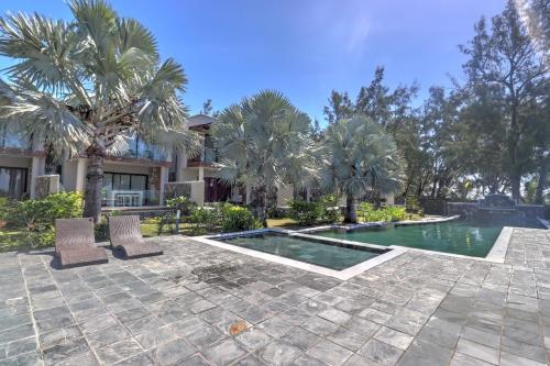 a swimming pool with two chairs and palm trees at SG5 l Le Turquoise - second line Beachfront in Cap Malheureux