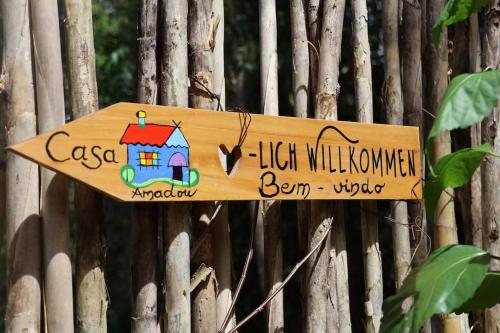 a wooden sign hanging on a fence at Casa Amadou com grande piscina em Boipeba in Ilha de Boipeba